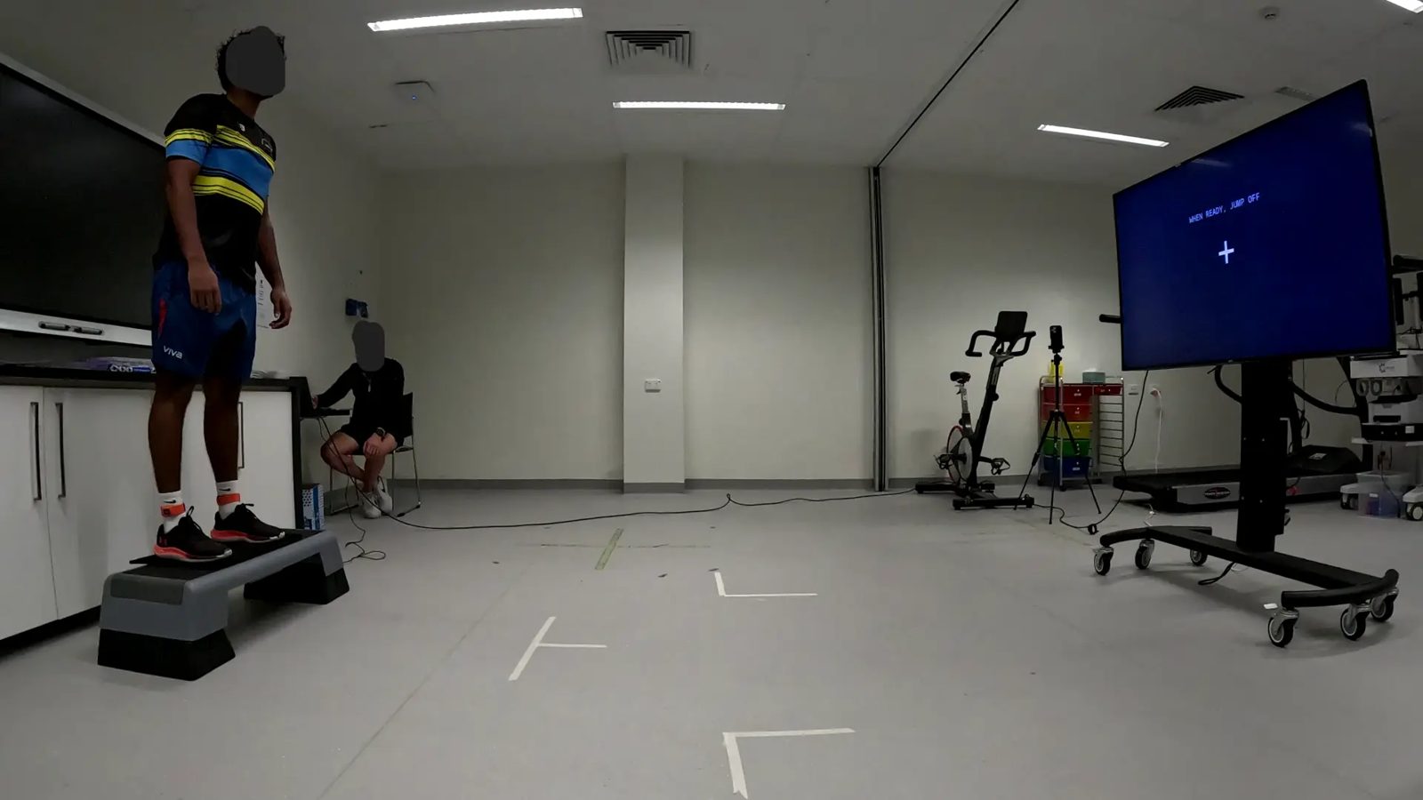 Participant standing on a TrampleTek mat on a step box in a Flinders University biomechanics lab.